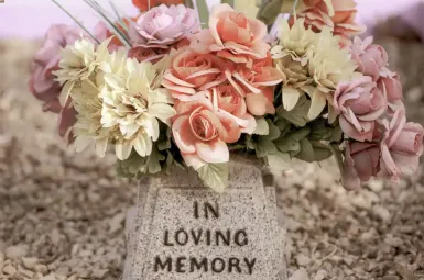Fiori su una pietra commemorativa con la scritta 'In Loving Memory'.