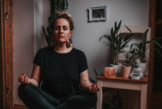Donna medita in una stanza con piante e una statua di Buddha.