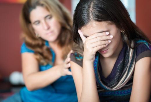 Donna conforta ragazza triste con mano sul suo braccio.