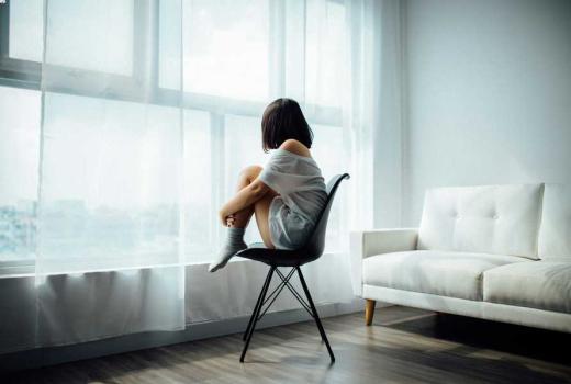 Ragazza seduta su una sedia, guarda fuori dalla finestra.