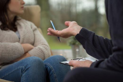 Conversazione tra due persone, una con una penna, l'altra con le braccia incrociate.