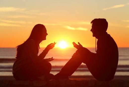 Due persone che parlano al tramonto sulla spiaggia.