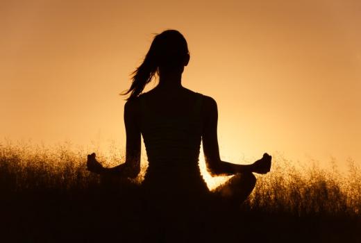 Persona che medita all'alba in un campo.