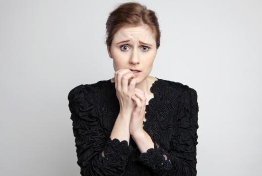 Donna preoccupata con le mani vicino alla bocca.