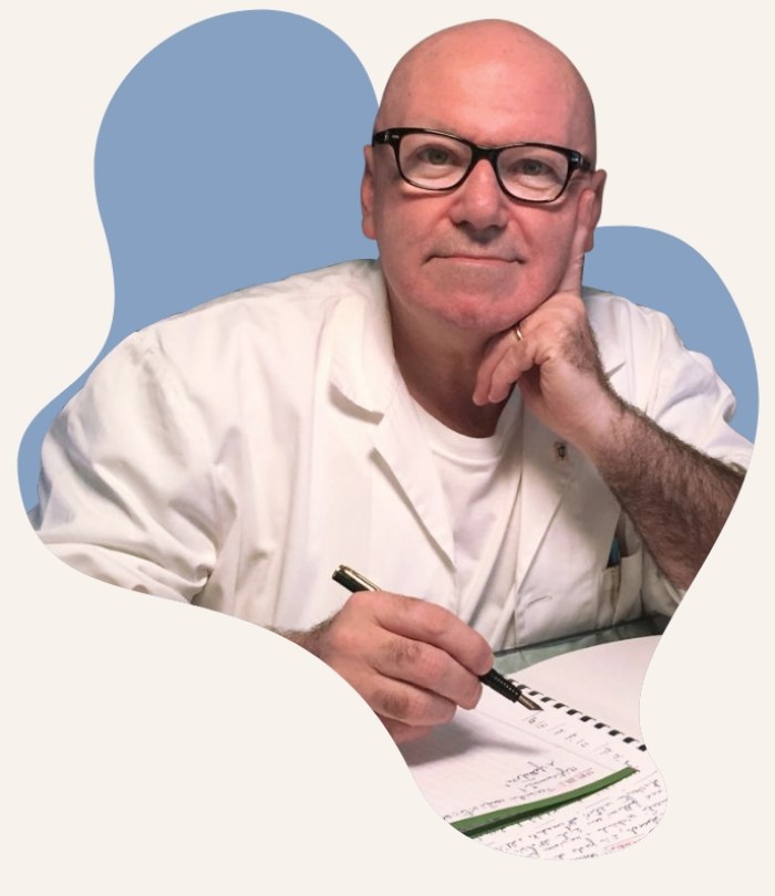 Medico con occhiali, camice bianco e penne nel taschino, sfondo astratto azzurro.
